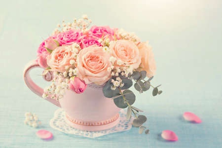 Pink roses in a teacup on a pastel blue backgroundの写真素材