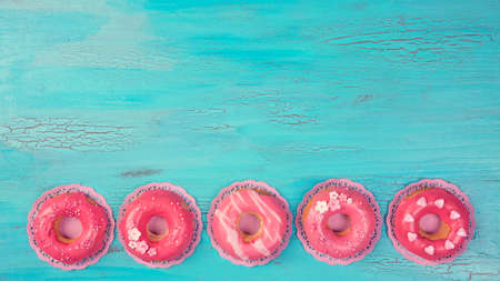 Pink colored donuts on a blue wooden backgroundの写真素材