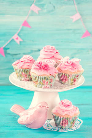 Cupcakes with pink flowers on a blue wooden backgroundの写真素材
