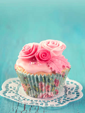 Cupcake with pink flowers on a blue wooden backgroundの写真素材