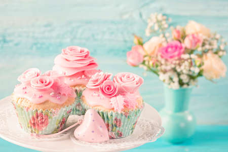 Cupcakes with pink flowers on a blue wooden backgroundの写真素材