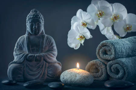 Buddha statue ,towels and stones on a black background