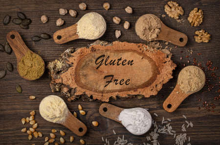 Gluten free flours in wooden spoons on a brown backgroundの写真素材