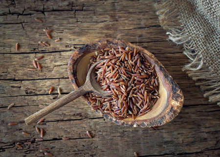 Camargue red rice in a bowl on wooden background