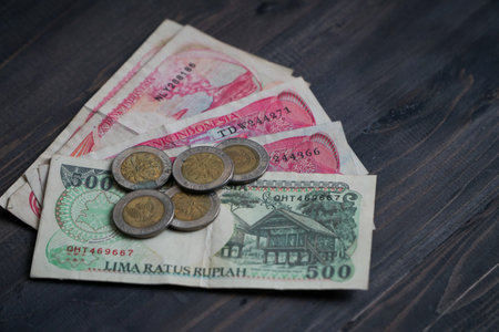 Indonesian rupiah notes 500 and 100 on a textured dark brown wooden background. Soft focus, selective focusの写真素材