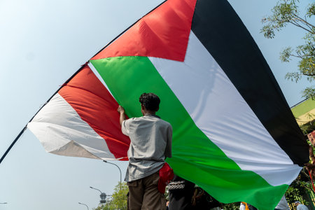 a young man holding a Palestinian flag protests against recent developments in the Gaza Strip