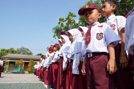 Banten, Indonesia - 18 December 2023 : Indonesian elementary school students in red and white uniforms line up to take part in the flag ceremony.のeditorial素材