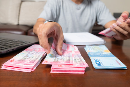 Close up of man's hands counting Indonesian rupiah notes and making notes, money financial management concept. Soft focus, Selective focusの写真素材