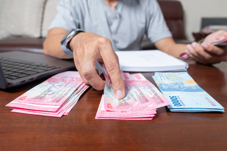 Close up of man's hands counting Indonesian rupiah notes and making notes, money financial management concept. Soft focus, Selective focusの写真素材