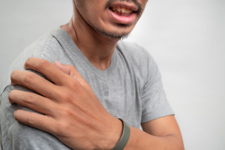 Man feels pain his shoulder isolated studio shot. isolated white backgroundの写真素材