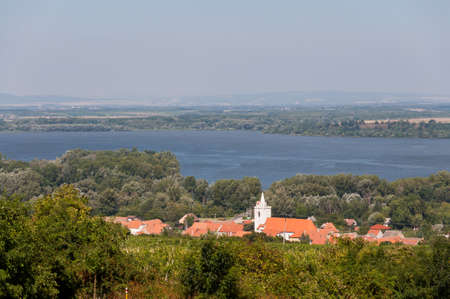 Church and village near lake, blue sky, trees.の写真素材