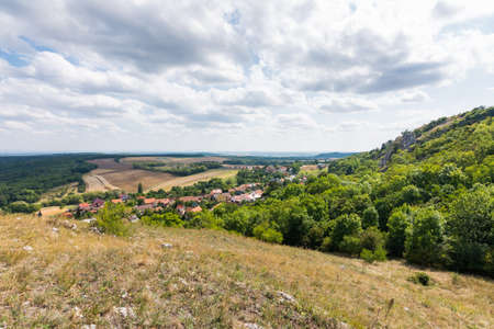 Landscape view of small village, meadow and agriculture. Forest on the right side with green trees, blue sky, the cloudsの写真素材