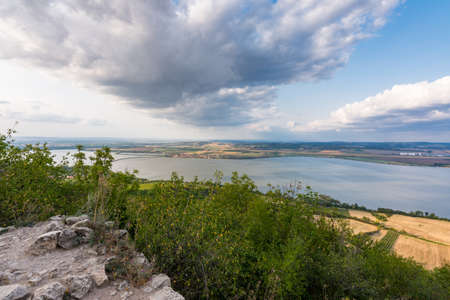 Landscape of village from castle on hill. Lake in foreground. Dramatic skyの写真素材