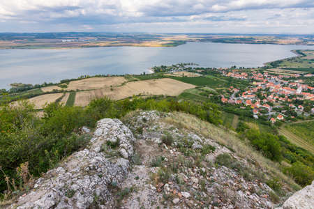 Landscape of village from castle on hill. Lake in foreground. Dramatic skyの写真素材