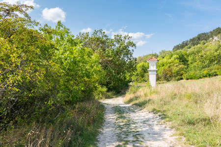 Calvary near the path with trees and bushes. Blue summer sky.の写真素材