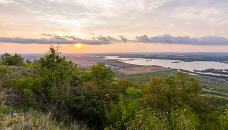 Sunset landscape panorama, hills in golden hour, small village in valley, beautiful colors and cloudsの写真素材