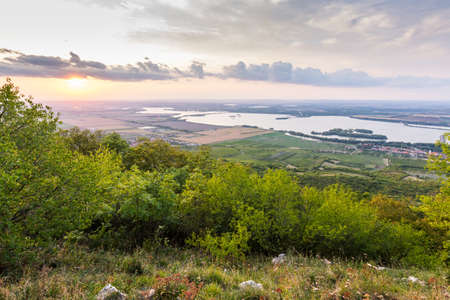 Sunset landscape panorama, hills in golden hour, small village in valley, beautiful colors and cloudsの写真素材