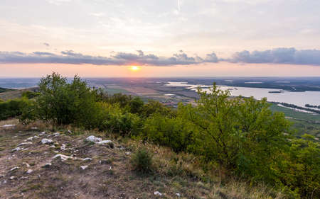 Sunset landscape panorama, hills in golden hour, small village in valley, beautiful colors and cloudsの写真素材