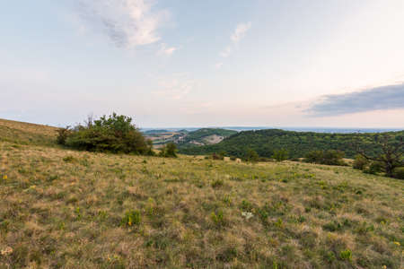Sunset landscape panorama, hills in golden hour, small village in valley, beautiful colors and cloudsの写真素材