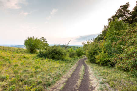 Sunset landscape panorama, hills in golden hour, small village in valley, beautiful colors and cloudsの写真素材