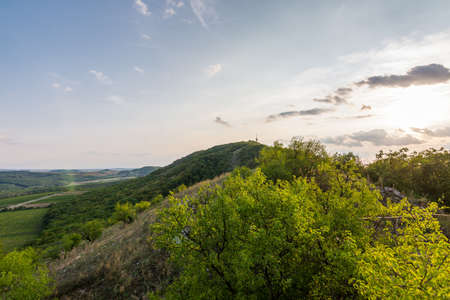 Sunset landscape panorama, hills in golden hour, small village in valley, beautiful colors and cloudsの写真素材