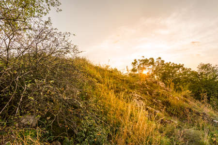 Sunset landscape panorama, hills in golden hour, small village in valley, beautiful colors and cloudsの写真素材