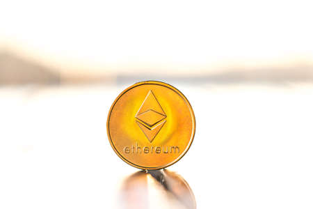 Ethereum gold color coin with sunset white background. Cryptocurrency virtual coinの写真素材