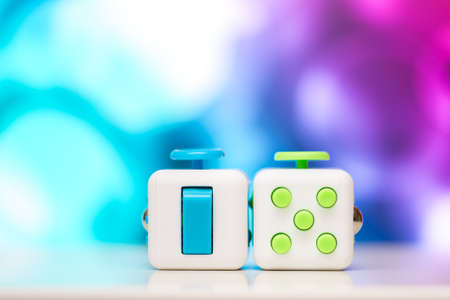 Fidget cube antis stress toy. Detail of finger play toy used for relax. Gadget placed on colorful bokeh background.の写真素材