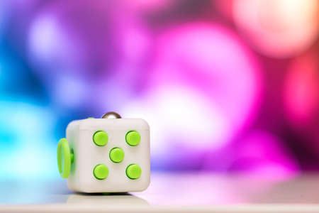 Fidget cube antis stress toy. Detail of finger play toy used for relax. Gadget placed on colorful...