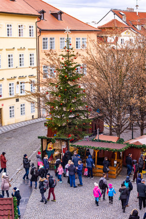 PRAGUE, CZECH REPUBLIC - 8.12.2018: Christmas market in Prague street. Christmas tree with small wooden shops near the Charles bridge. Peoples buy gifts.のeditorial素材
