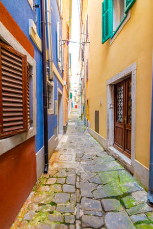 Old and narrow streets in Piran city, Slovenia. Ancient medieval streets in town center of famous European city, near the adriatic sea. Old houses with wooden windows and doors, magical atmosphereの写真素材
