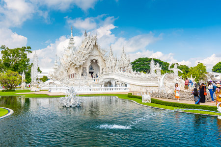 CHIANG RAI, THAILAND - 6.11.2019: Tourists visit famous white temple (Wat Rong Khun) near Chiang Rai city. White temple with bridge above damned souls of sinners, path to the heaven. Blue sky.のeditorial素材