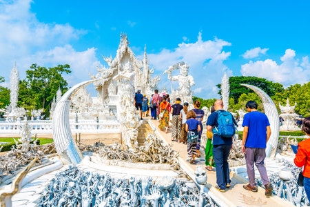 CHIANG RAI, THAILAND - 6.11.2019: Tourists visit famous white temple (Wat Rong Khun) near Chiang Rai city. White temple with bridge above damned souls of sinners, path to the heaven. Blue sky.のeditorial素材