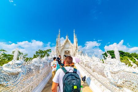 CHIANG RAI, THAILAND - 6.11.2019: Tourists visit famous white temple (Wat Rong Khun) near Chiang Rai city. White temple with bridge above damned souls of sinners, path to the heaven. Blue sky.のeditorial素材