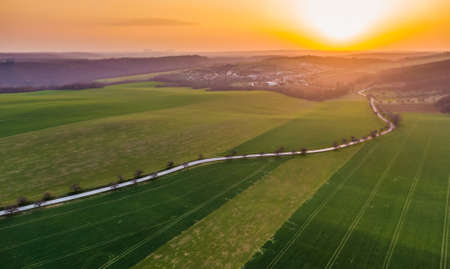 Aerial view of agriculture land during beautiful sunset. Fields and meadow with the small village in...