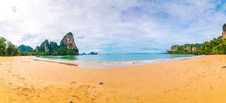 Panoramic view of famous Railay beach, Krabi Thailand. Big limestone rock above pure turquoise sea with boats for tourists. Tropical paradise at Andaman sea with white sand. Vibrant colors.の写真素材