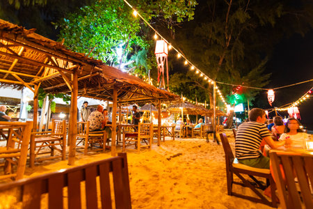 Koh Lanta, Thailand - 10.11.2019: View of small beach bar at night, at Ko Lanta island, Thailand. Chairs and tables are placed on sand. Many lightbulb are lighting above bar. Relaxation near seaのeditorial素材