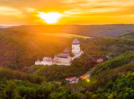 Aerial view of beautiful sunset over the Karlstejn castle, Czech Republic. Drone shot of ancient castle with near forest. Castle in gothic style was build by emperor of Rome rise, Charles IV.のeditorial素材