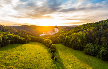 Aerial view of beautiful sunset over the Karlstejn castle, Czech Republic. Drone shot of ancient castle with near forest. Castle in gothic style was build by emperor of Rome rise, Charles IV.のeditorial素材