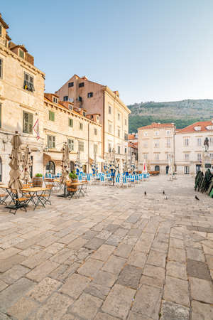 Table near the restaurants at Dubrovnik old town square. Summer morning after sunrise. Ancient town in Croatia.の写真素材