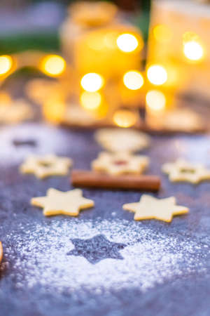 Christmas sweets and cookies placed on gray desk. Winter decorations, pine tree and cone. Concept of christmas, gifts and holidays. Glowing lights in the background.の写真素材