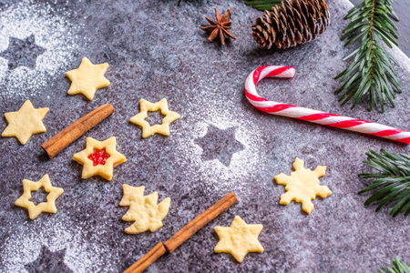 Christmas sweets and cookies in the form of a Christmas tree placed on a gray desk with pine cone and branch on the side. Winter and christmas decorations, cinnamon, sugar and star anise.の写真素材