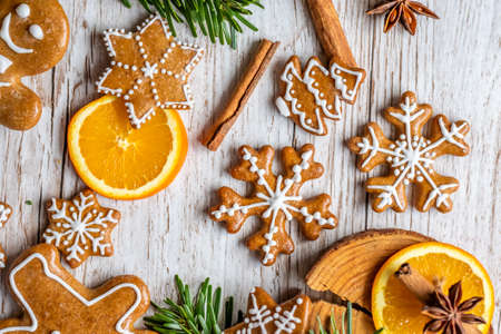 Christmas gingerbread and sweets are placed on a wooden desk. Cookies and sweet food in the shape of stars and snow flakes. Winter theme, rustic style. Pine trees on the side. Candy stick and other spice.の写真素材