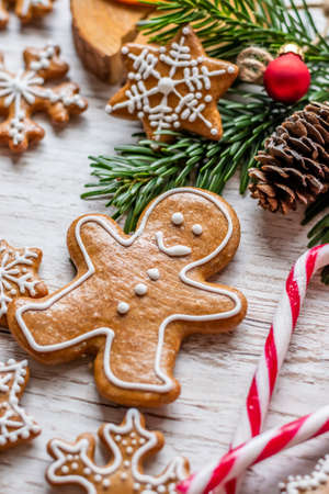 Christmas gingerbread and sweets are placed on a wooden desk. Cookies and sweet food in the shape of stars and snow flakes. Winter theme, rustic style. Pine trees on the side. Candy stick and other spice.の写真素材