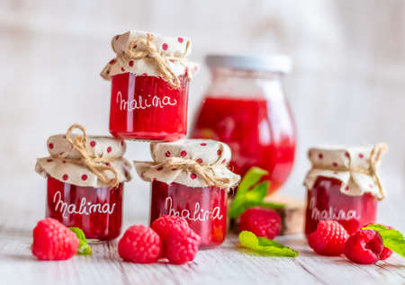 Raspberry marmalade in small glasses is placed on a wooden desk. Homemade jam from fresh...