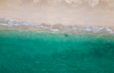 Aerial drone view (top down) to sea waves and white sand. Turquoise blue water, tropical theme....