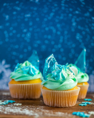 Homemade cupcake of blue color placed on wooden desk. Winter and christmas theme, snowflakes on cream with blue ice. Fresh and home baked sweet.の写真素材