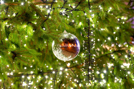 A beautiful glass ornament hanging on a Christmas tree, reflecting the lively atmosphere of the square in Pilsen, capturing the essence of the holiday spiritの写真素材