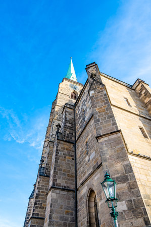 A photograph of the Cathedral of St. Bartholomew in Plzen, Czech Republic. This Gothic cathedral with its iconic tower stands proudly, surrounded by historic buildings, offering a stunning viewの写真素材