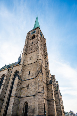 A photograph of the Cathedral of St. Bartholomew in Plzen, Czech Republic. This Gothic cathedral with its iconic tower stands proudly, surrounded by historic buildings, offering a stunning viewの写真素材